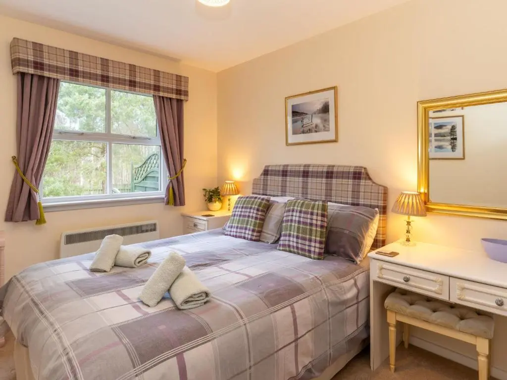 a bedroom with a bed and a desk and a window at Holiday Home Falcon Lodge by Interhome in Aviemore
