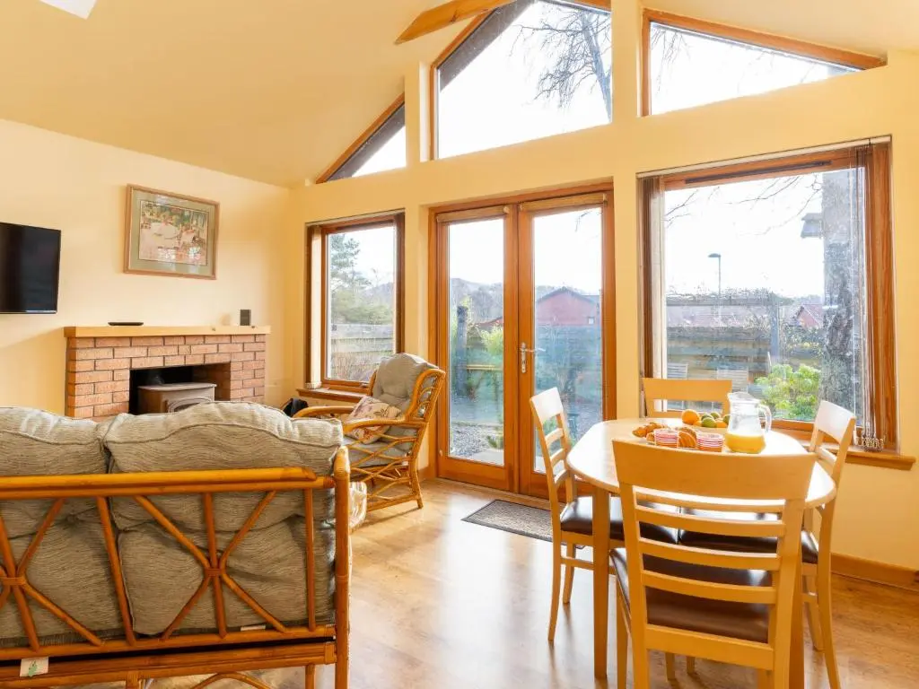 a living room with a table and chairs and a fireplace at Holiday Home Skye Premier by Interhome in Aviemore