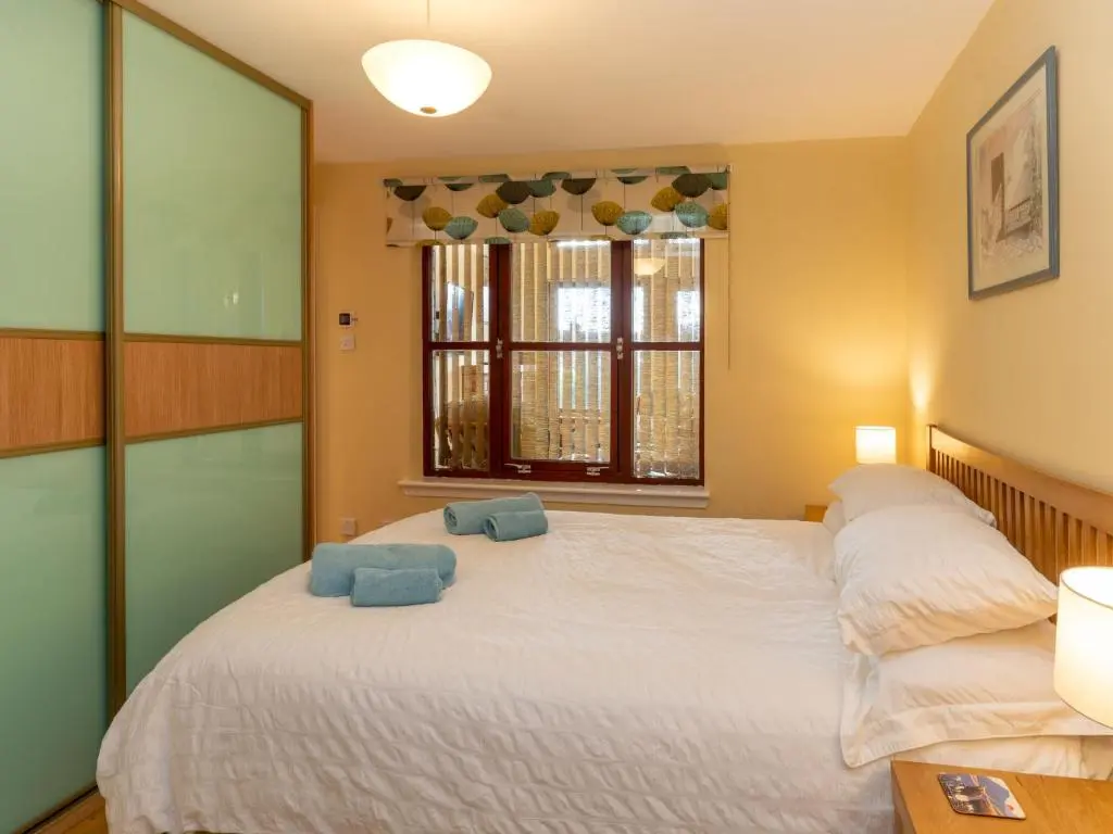 a bedroom with a bed with two blue towels on it at Holiday Home Skye Premier by Interhome in Aviemore