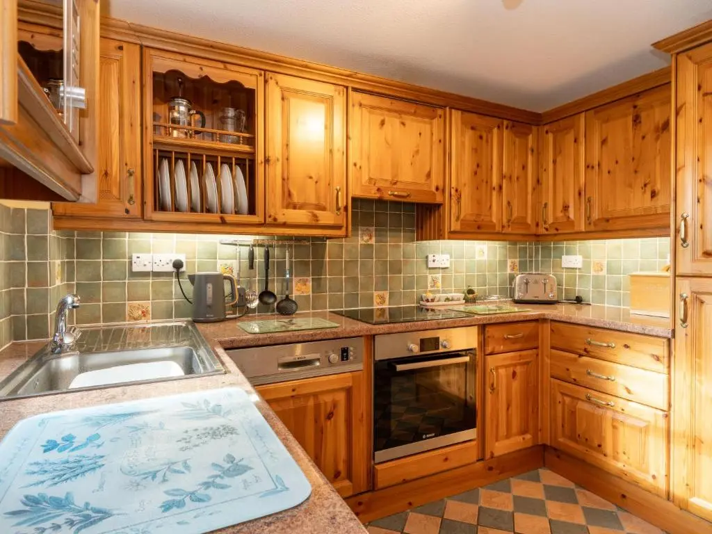 a kitchen with wooden cabinets and a sink at Holiday Home Skye Premier by Interhome in Aviemore