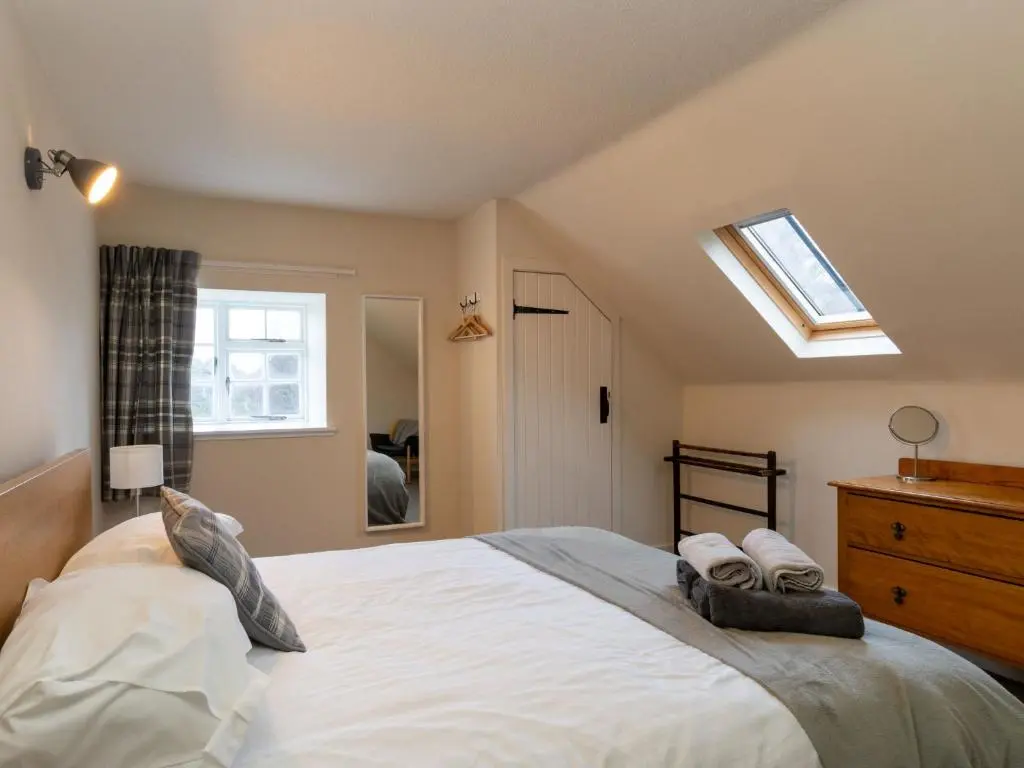 a bedroom with a large white bed and a skylight at Holiday Home 2 Railway Cottage by Interhome in Aviemore