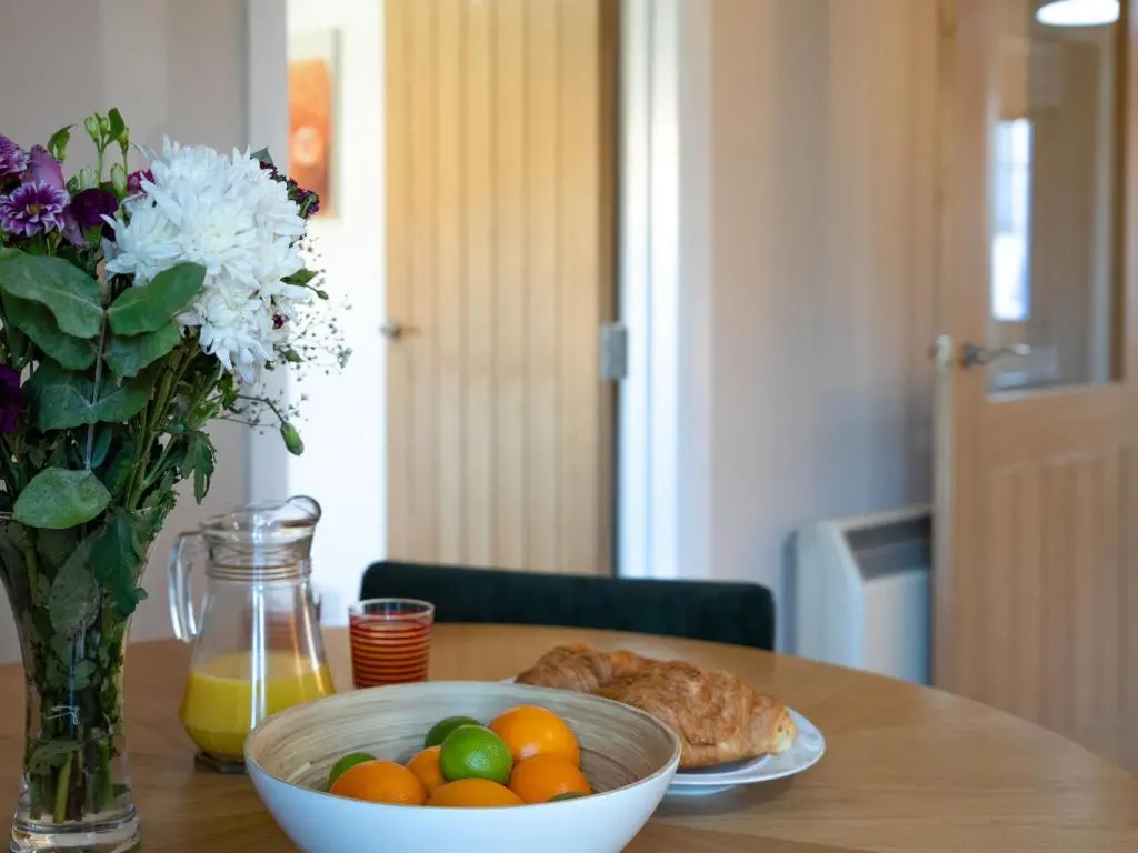a table with a bowl of fruit and a vase of flowers at Apartment The Bruach by Interhome in Aviemore