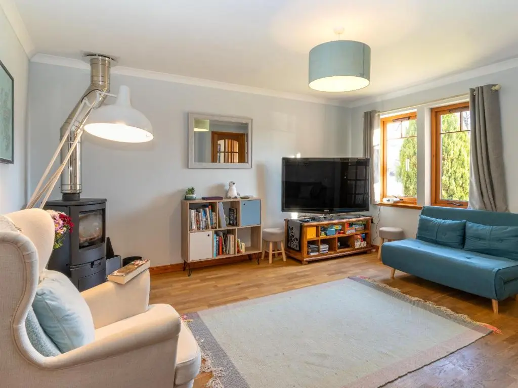 a living room with a blue couch and a tv at Holiday Home Cosagach Cottage by Interhome in Aviemore