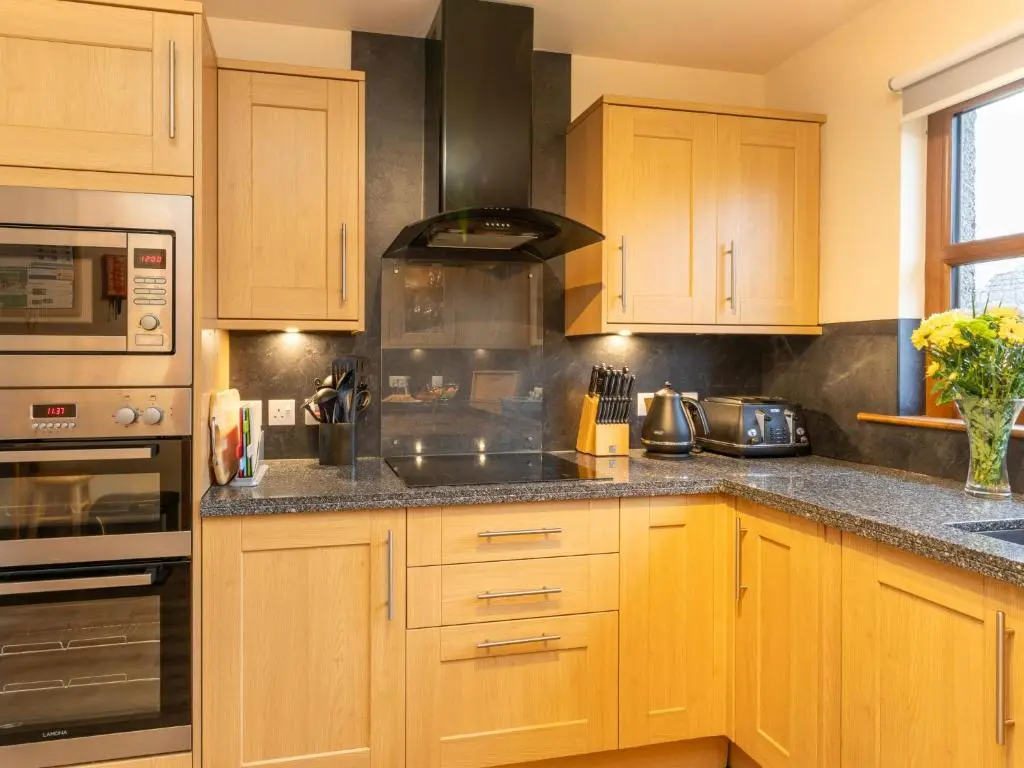 a kitchen with wooden cabinets and a stove at Holiday Home Braeriach by Interhome in Aviemore