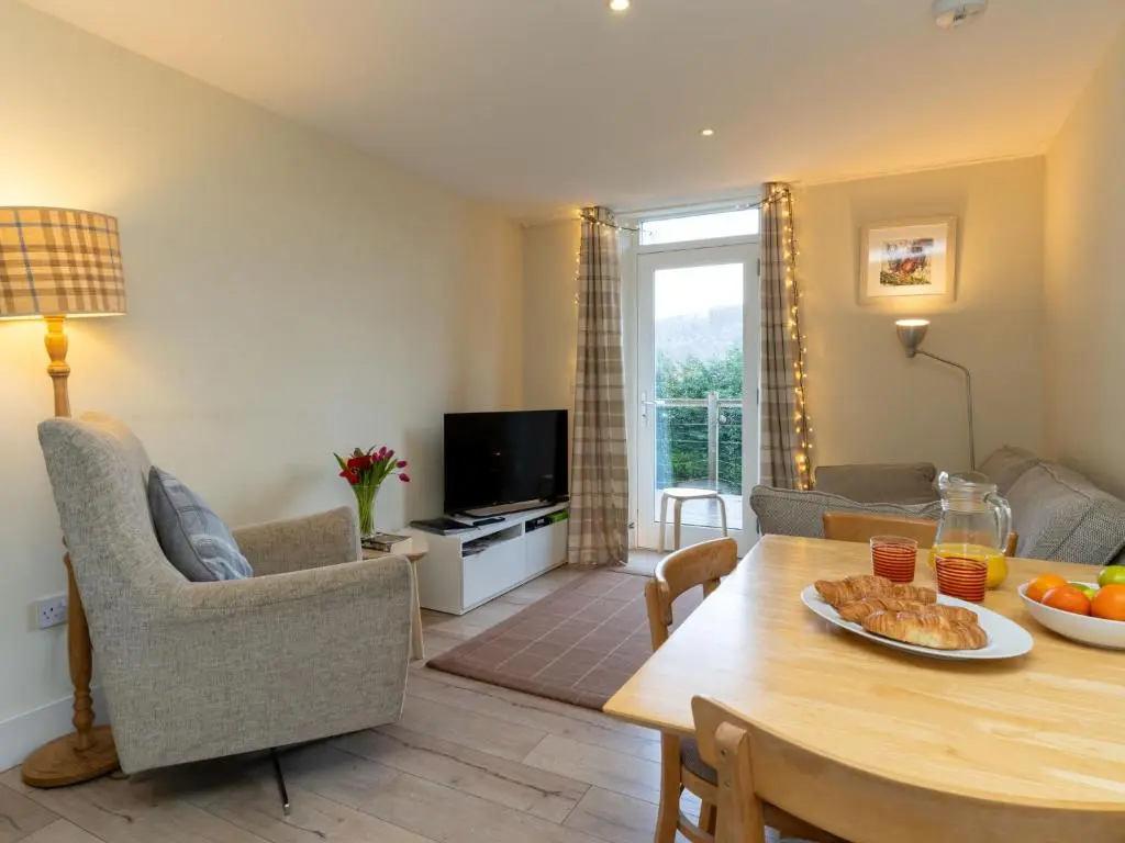 a living room with a table and a tv at Holiday Home 1 Railway Cottage by Interhome in Aviemore