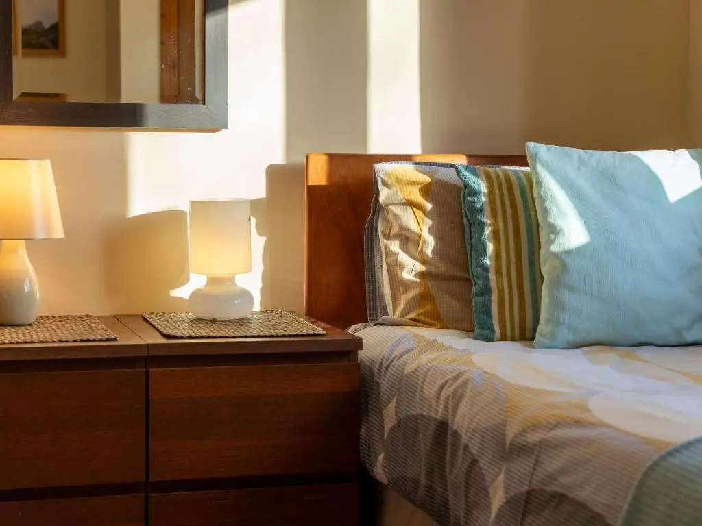a bedroom with a bed with a lamp on a dresser at Holiday Home Culduthel by Interhome in Aviemore