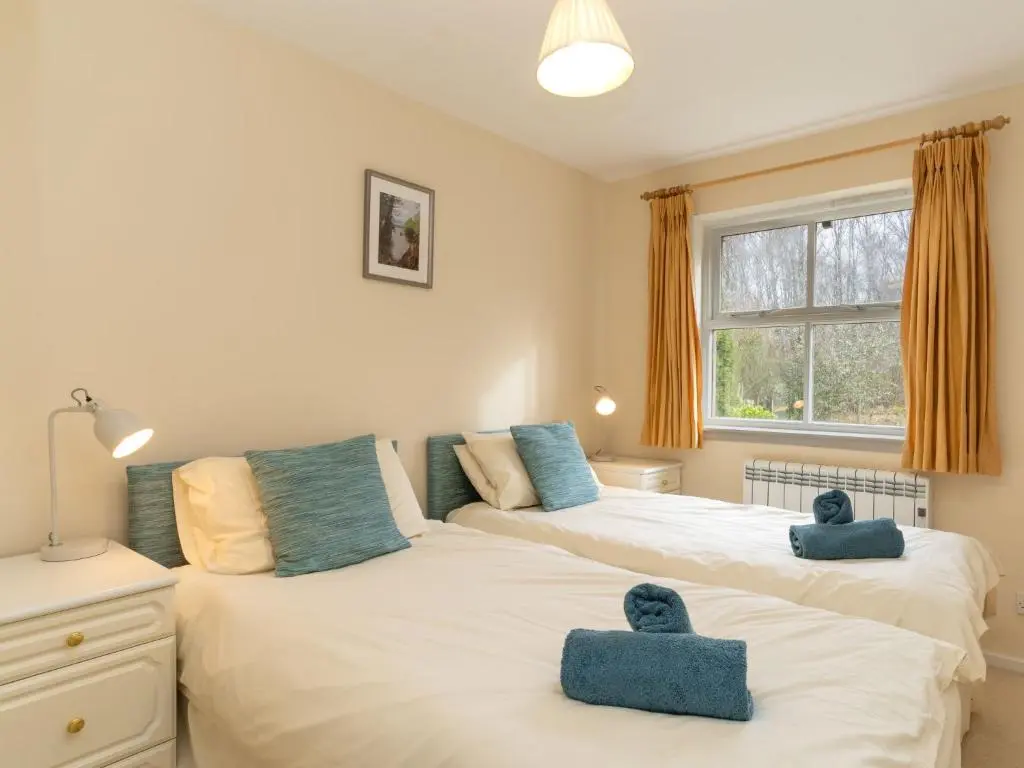 two beds in a bedroom with two blue towels at Holiday Home Glenpark by Interhome in Aviemore
