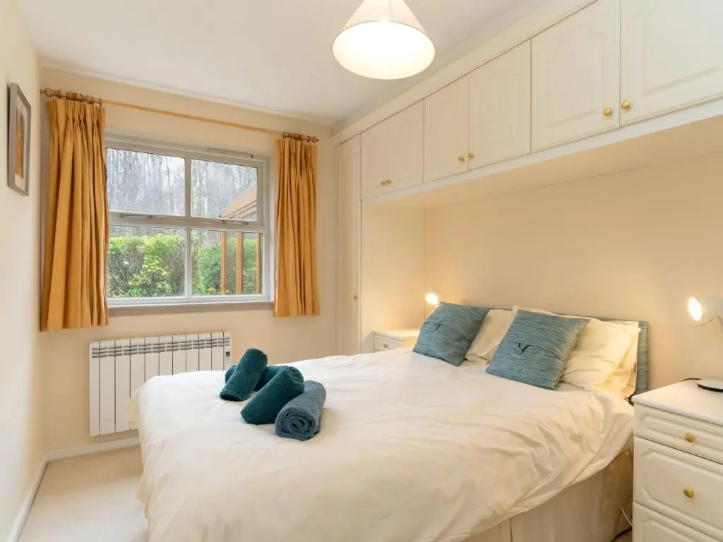 a bedroom with a large white bed with blue towels on it at Holiday Home Glenpark by Interhome in Aviemore