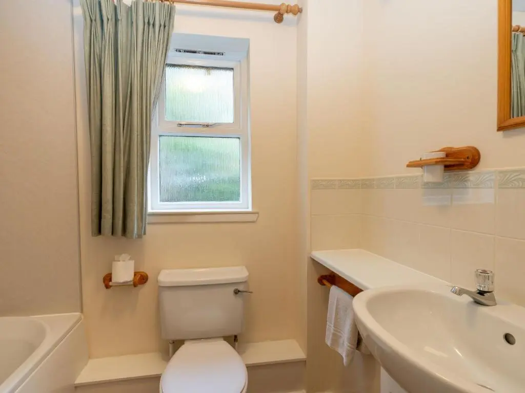 a white bathroom with a toilet and a sink at Holiday Home Glenpark by Interhome in Aviemore