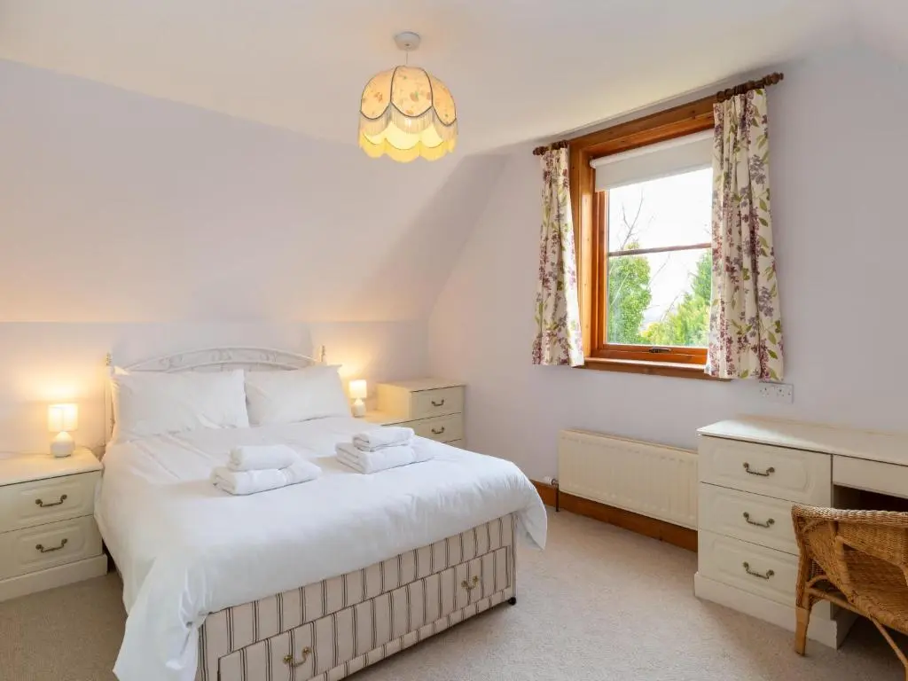 a bedroom with a large white bed and a window at Holiday Home Lower Curr by Interhome in Skye of Curr