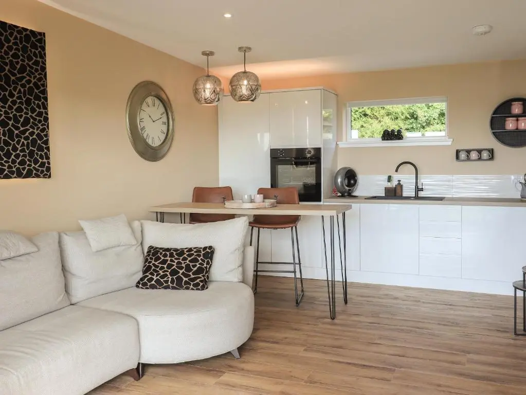 a living room with a couch and a kitchen at Core-na-bye in Inverness