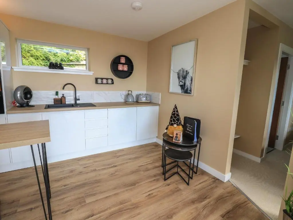 a kitchen with a counter and a table and a sink at Core-na-bye in Inverness