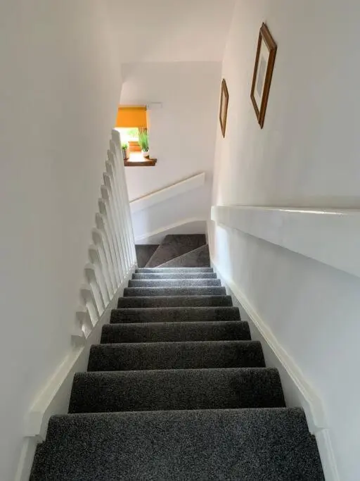 a staircase in a building with black carpeted stairs at No.46, comfortable 2 bedroom property in Rothes