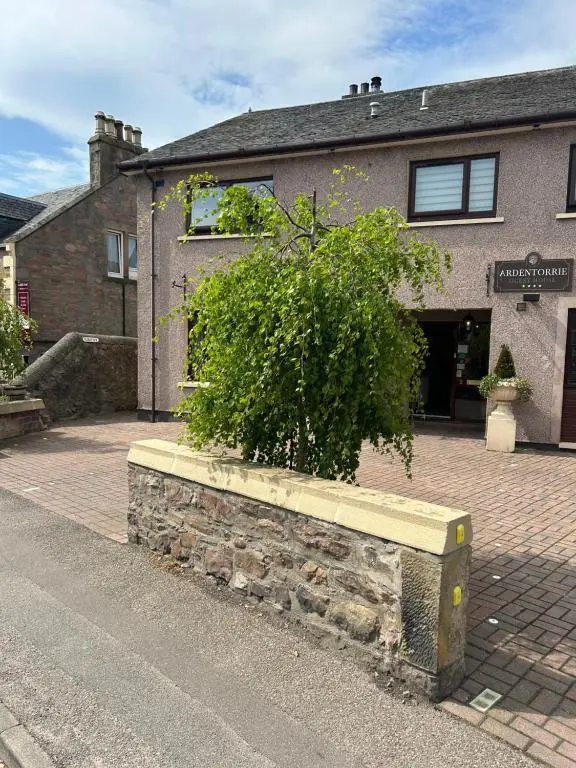 a bush in a stone planter in front of a building at Floras View in Inverness