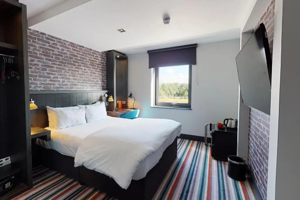 a bedroom with a large bed and a brick wall at Village Hotel Aberdeen in Aberdeen