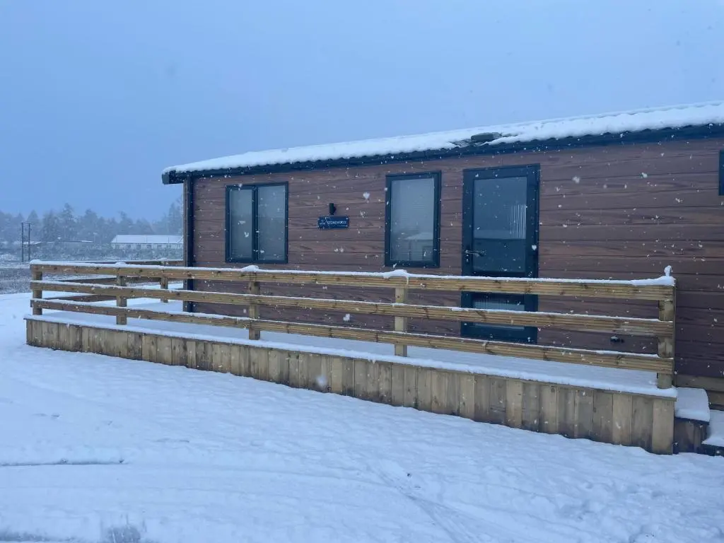 a log cabin in the snow with a fence at The Drey in Grantown on Spey