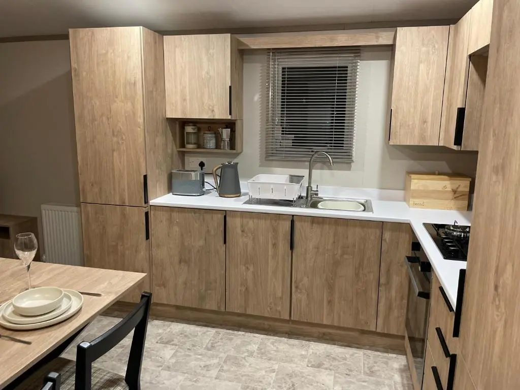 a kitchen with wooden cabinets and a table with a sink at The Drey in Grantown on Spey