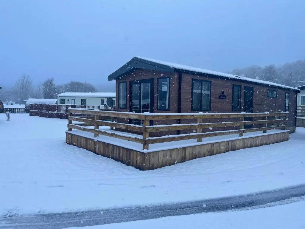 a cabin in the snow with a snow covered yard at The Drey in Grantown on Spey