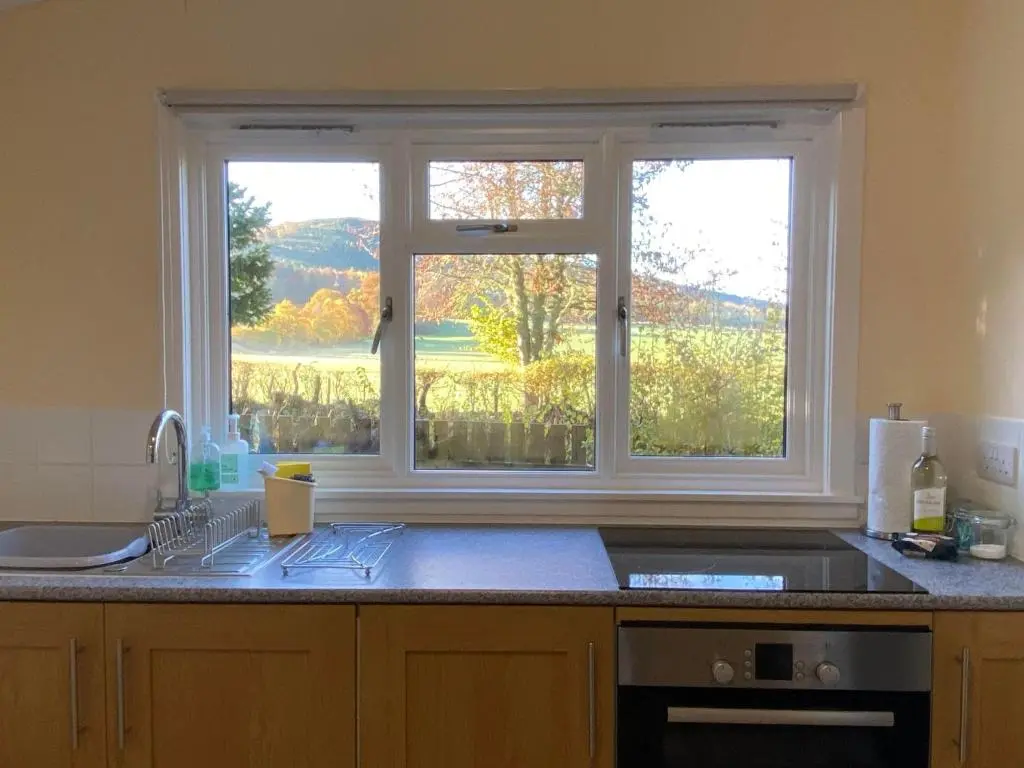 a kitchen with a sink and a window with a view at Burnside Chalet on Reelig Estate in Kirkhill