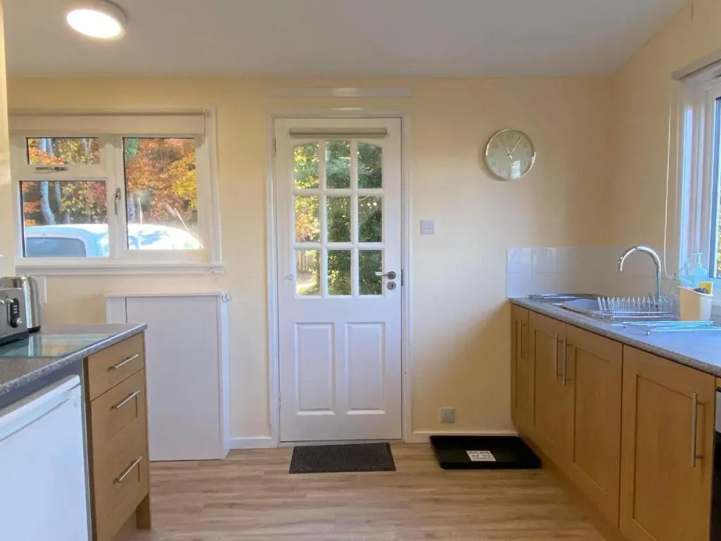 a kitchen with a white door and a sink at Burnside Chalet on Reelig Estate in Kirkhill