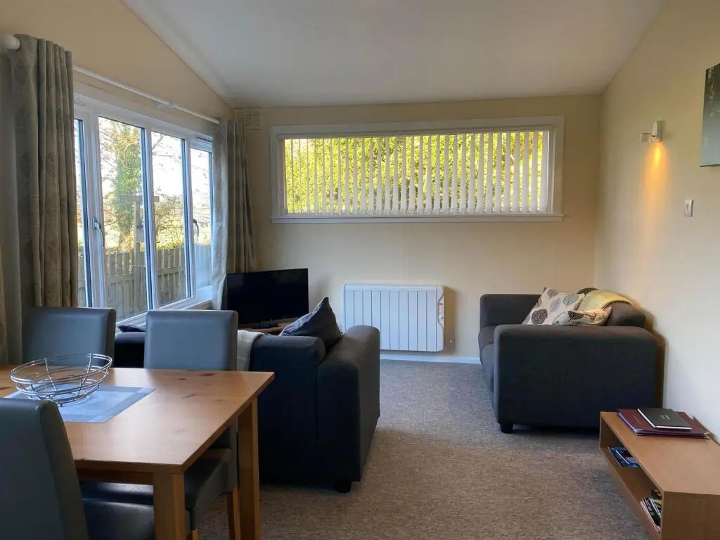 a living room with couches and a table at Burnside Chalet on Reelig Estate in Kirkhill