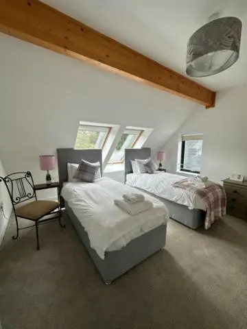 a bedroom with two beds and a chair at Highland Holiday Home in Contin