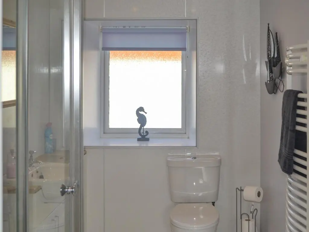 a bathroom with a window with a figurine of a woman at Sandy Bay in Portmahomack