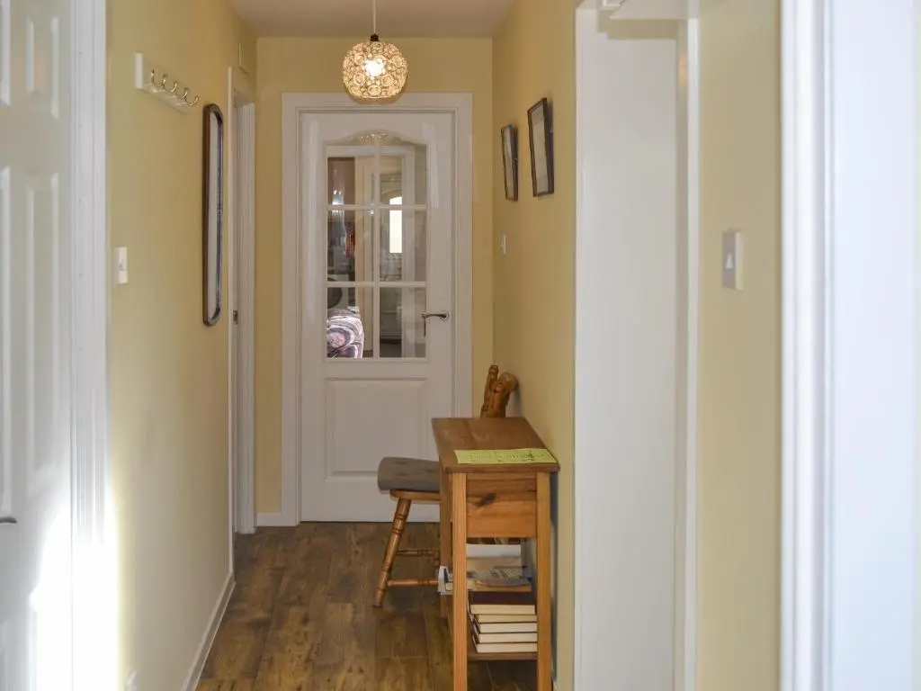 a hallway with a table and a door at Sandy Bay in Portmahomack
