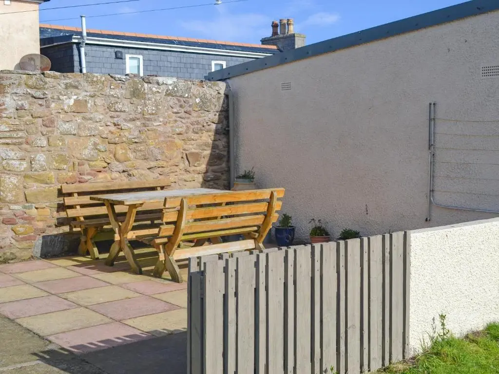 a wooden table and bench next to a stone wall at Sandy Bay in Portmahomack