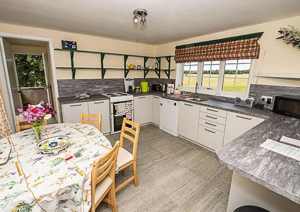 a kitchen with a table and a table and chairs at West Lodge 3 bedrooms, near golf course and river in Turriff