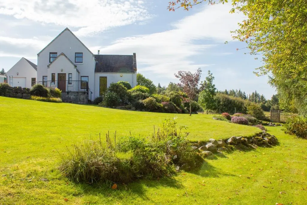 a house on a hill with a green yard at Carriden in Insh