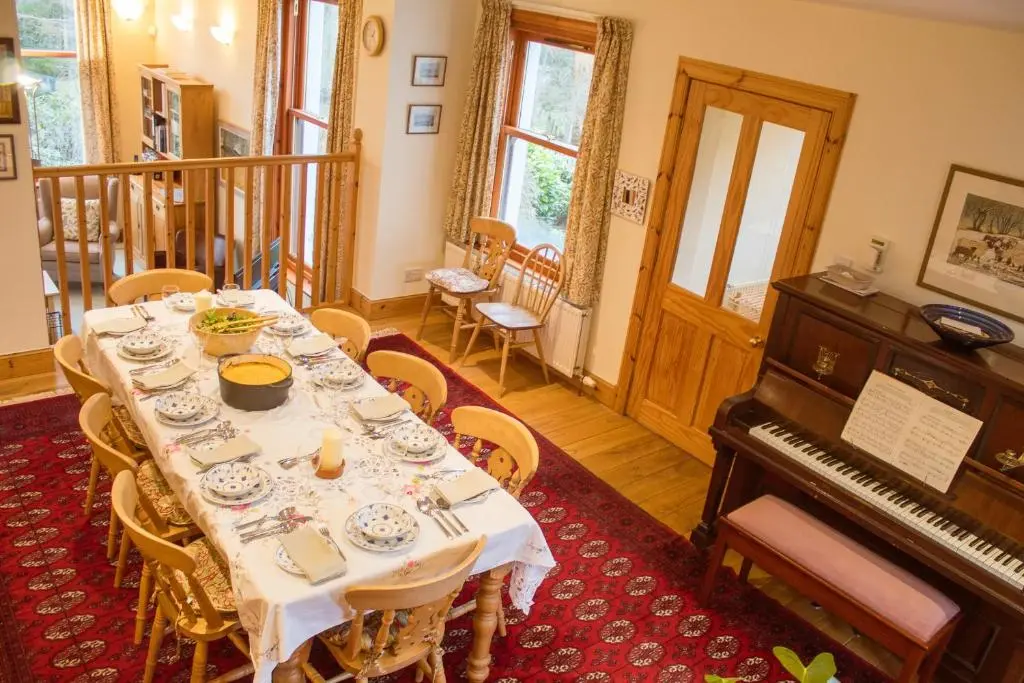 a dining room with a table and a piano at Carriden in Insh