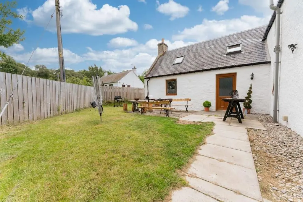 a white cottage with a patio and a fence at Jacobite Lodge by The House of Danu in Kingussie