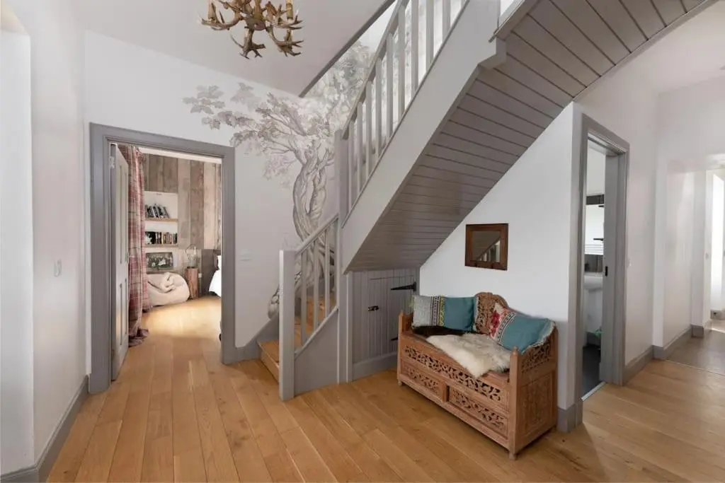 a room with a staircase with a couch and a stair case at Jacobite Lodge by The House of Danu in Kingussie