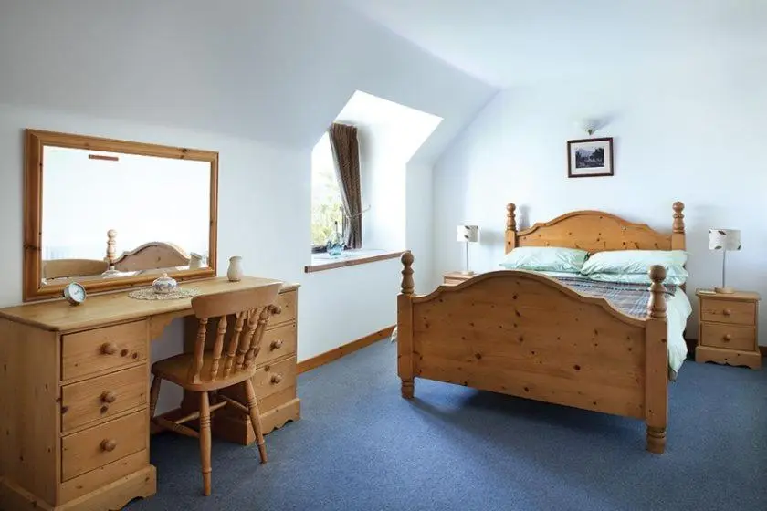 a bedroom with a bed and a desk and a mirror at Red Kite in Belmaduthy