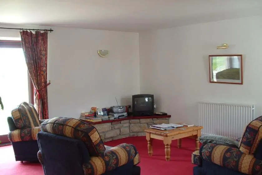 a living room with two chairs and a table and a tv at Red Kite in Belmaduthy