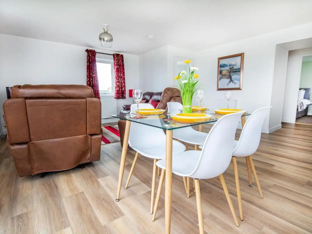 a dining room with a glass table and white chairs at Cranberry Cottage in Wick