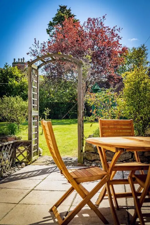 a wooden table and chairs sitting next to a garden at Fonthill Bed and Breakfast Nairn in Nairn