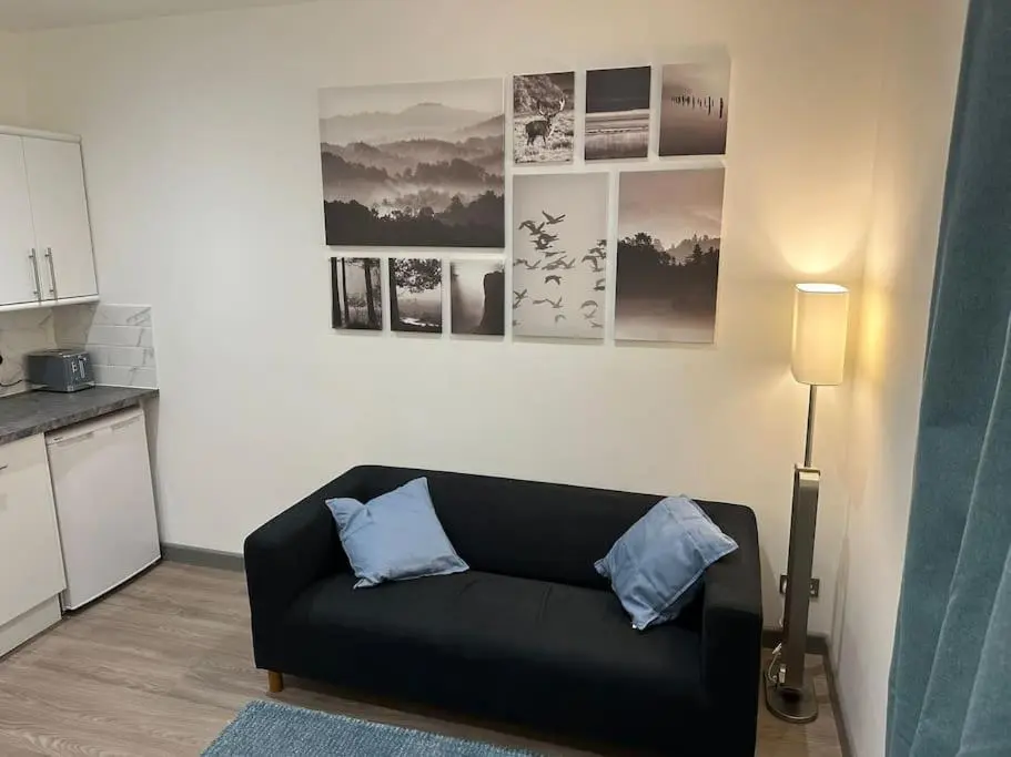 a living room with a black couch and a kitchen at Riverview Apartment, Inverness in Inverness
