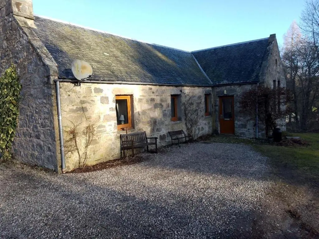 a stone house with two benches in front of it at Old School in Kingussie