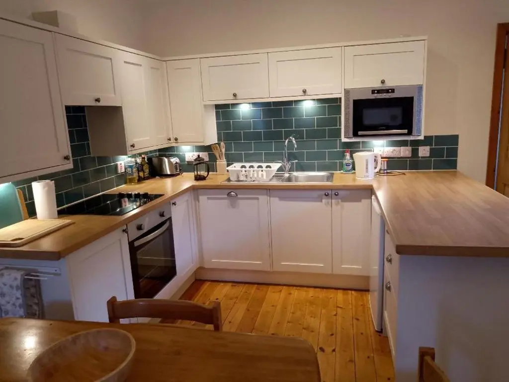 a kitchen with white cabinets and a table in it at Old School in Kingussie