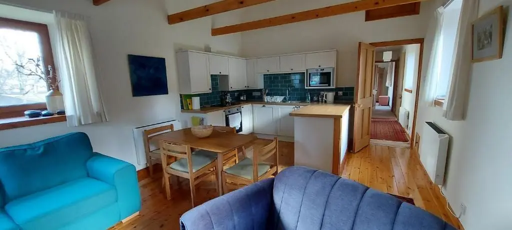 a living room with a blue couch and a table at Old School in Kingussie