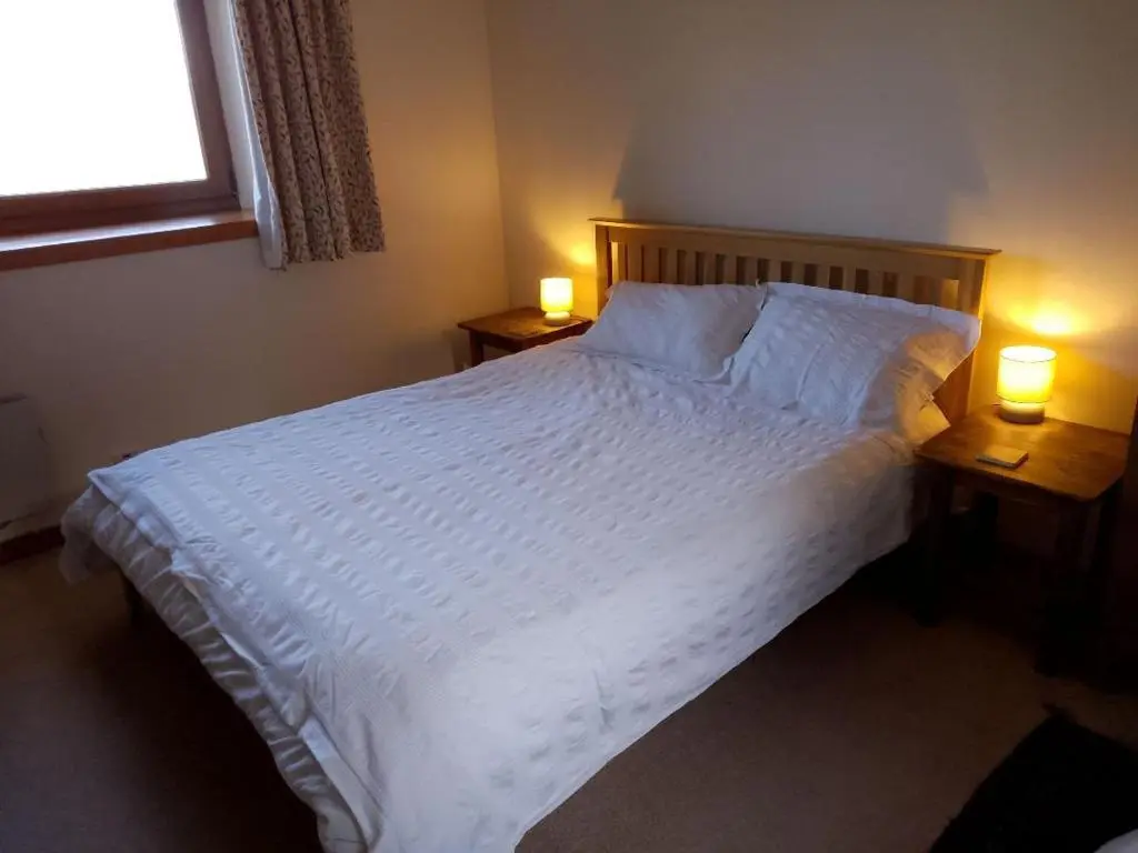 a bedroom with a large white bed with two lamps at Old School in Kingussie