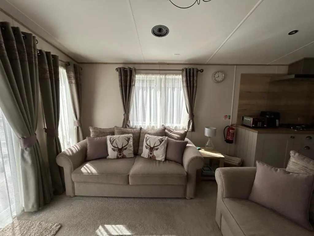 a living room with a couch and a chair at Lodge 2 The Wee Hut Aviemore in Aviemore