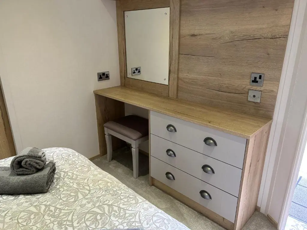 a bedroom with a dresser and a mirror at Lodge 2 The Wee Hut Aviemore in Aviemore