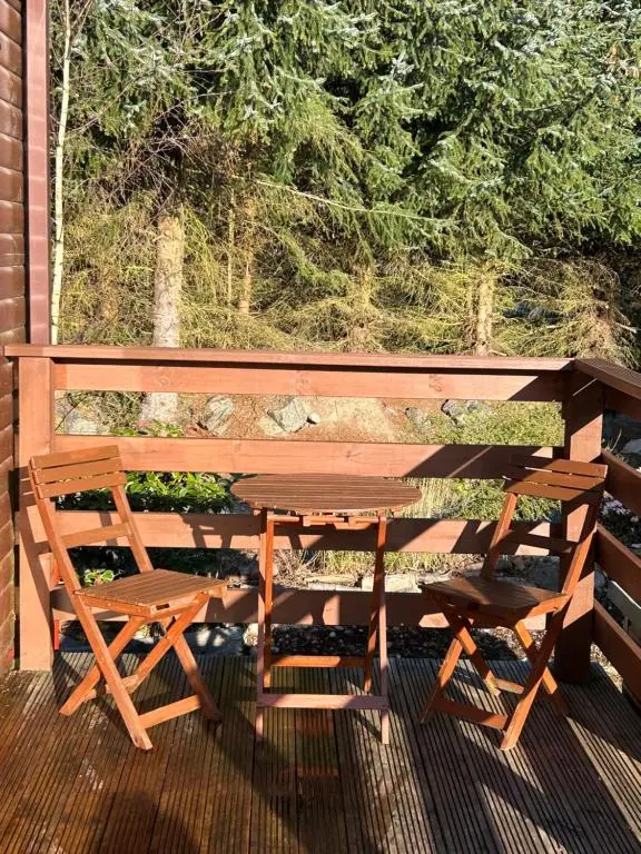 a wooden table and a bench on a deck at Lodge 2 The Wee Hut Aviemore in Aviemore