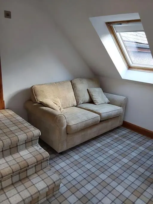 a couch in the corner of a room with a window at Top Floor Flat Ceol Na Mara (Music of the Sea) in Rosemarkie