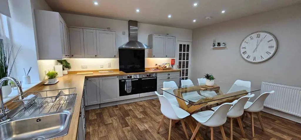 a kitchen with a table and chairs and a clock on the wall at Antfield House in Inverness