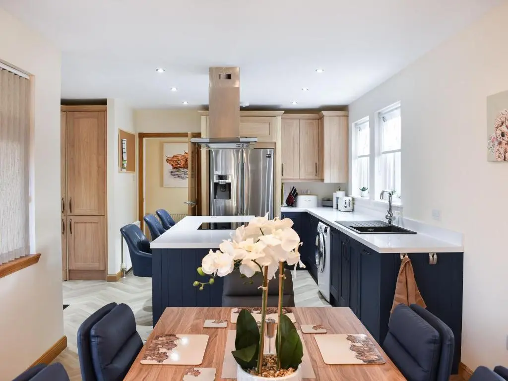 a kitchen with a table and blue cabinets at Rycon in Turriff