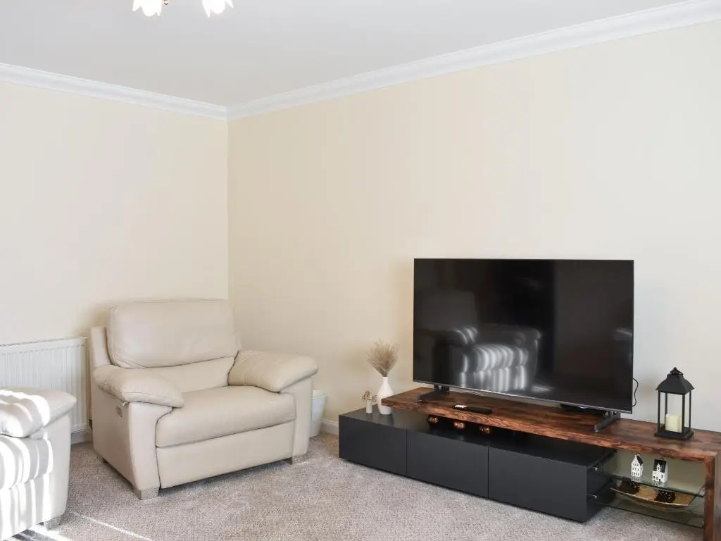 a living room with a flat screen tv and a chair at Rycon in Turriff